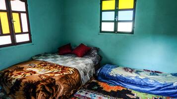 A bedroom with a bed, a window, and a wall.