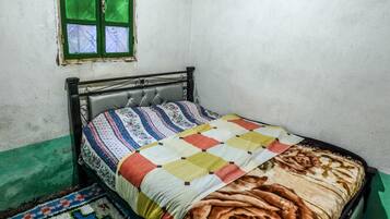 A small, single-bed room with a metal headboard, a colorful quilt, and a patterned rug.