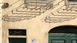 Fachada de edificio con puerta verde, buzón y placa con número.