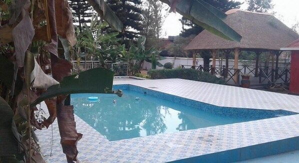A swimming pool with a tiled deck, surrounded by tropical plants and a gazebo. - Zenith Hotel Kigali (Kigali)