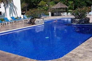 Una piscina al aire libre, sillones reclinables de piscina