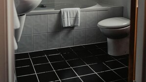 A bathroom with a large bathtub, a toilet, and a sink. - Broadford Hotel (Isle of Skye)