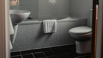 Een badkamer met een groot bad, een toilet en een wastafel.