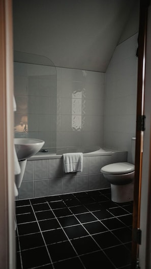 A bathroom with a large bathtub, a toilet, and a sink.