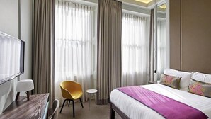 A hotel room with a bed, a desk, a chair, and a small table. - Arbor Hyde Park (London)