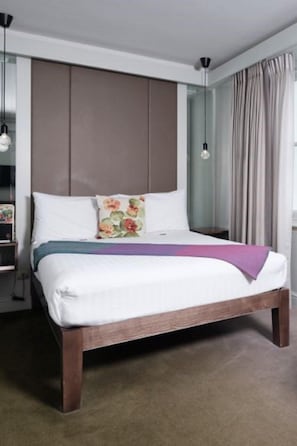 A neatly made bed with a wooden frame, white bedding, and decorative pillows.