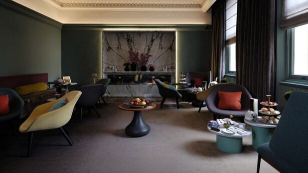 A modern lounge area with a marble fireplace, comfortable seating, and a small dining table with snacks. - Arbor Hyde Park (London)