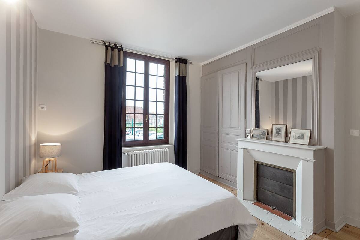 Quarto com cama, lareira, janela com cortinas e radiador.