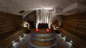 A rustic wooden room with a central barrel, birch branches, and candles.