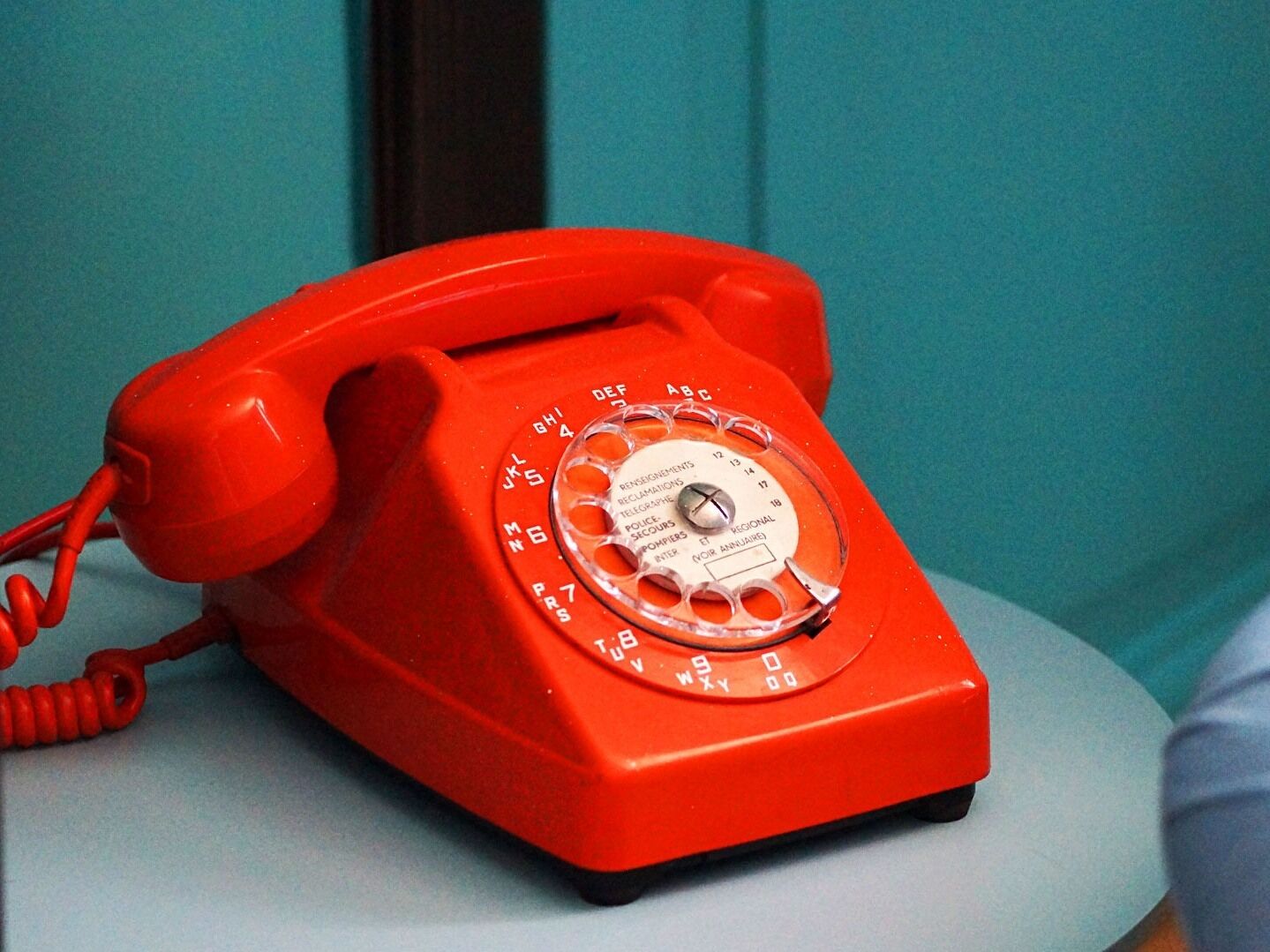 A red rotary dial telephone on a table.