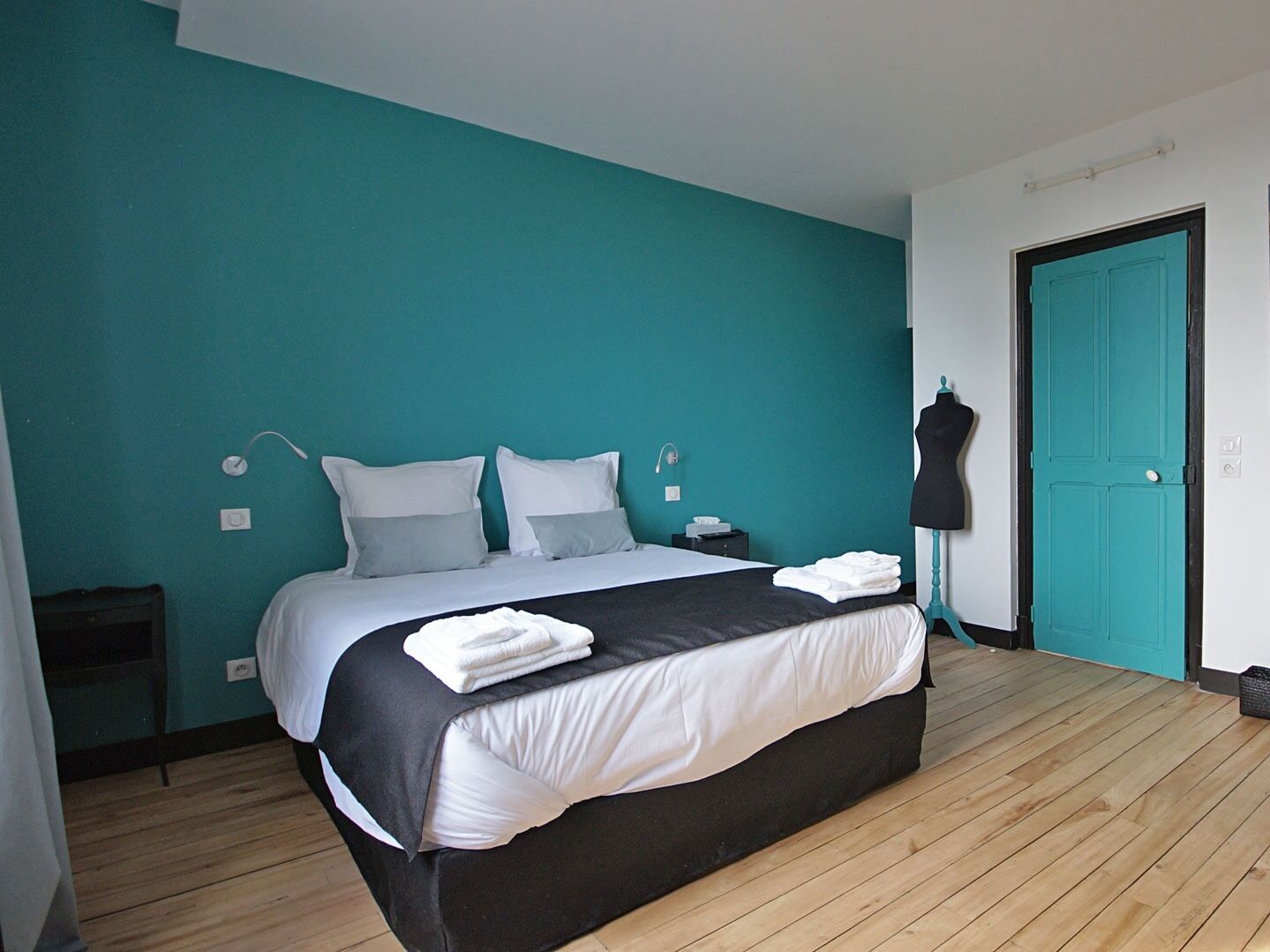 A bedroom with a bed, a dresser, a wardrobe, and a mannequin.
