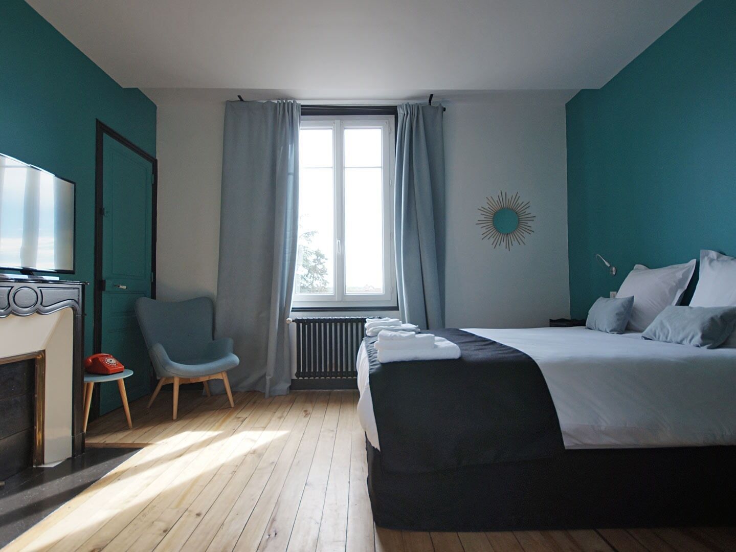 Une chambre à coucher avec un lit, une chaise, une télévision et une cheminée.