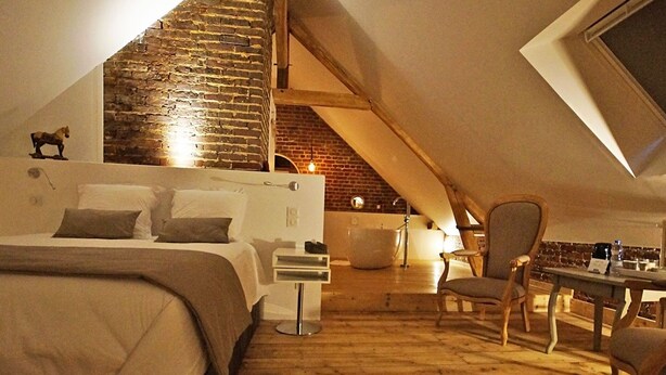 A cozy attic bedroom with a bed, a chair, and a table.