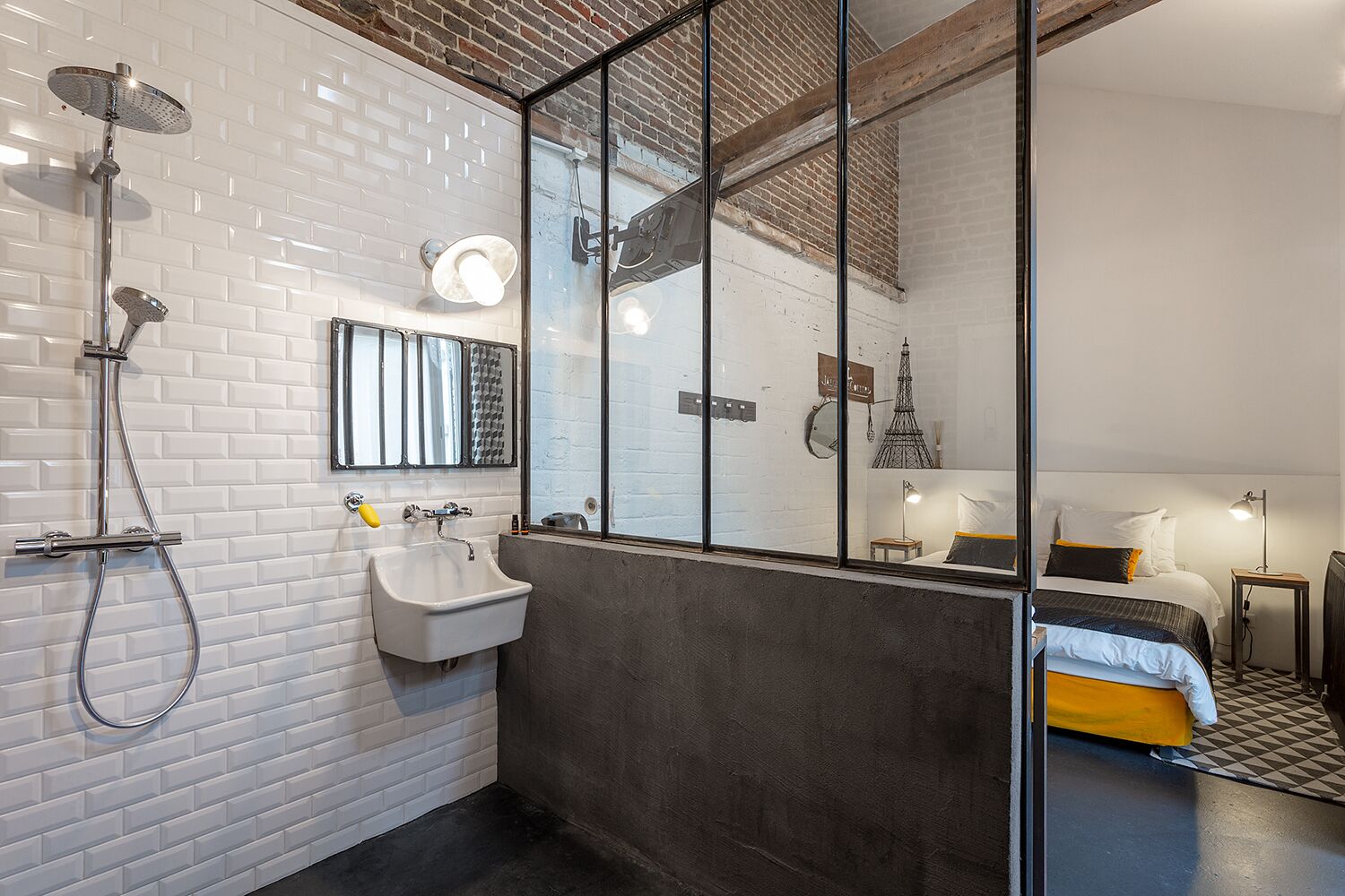 A modern bathroom with a white tiled wall, a sink, a shower, and a large mirror.