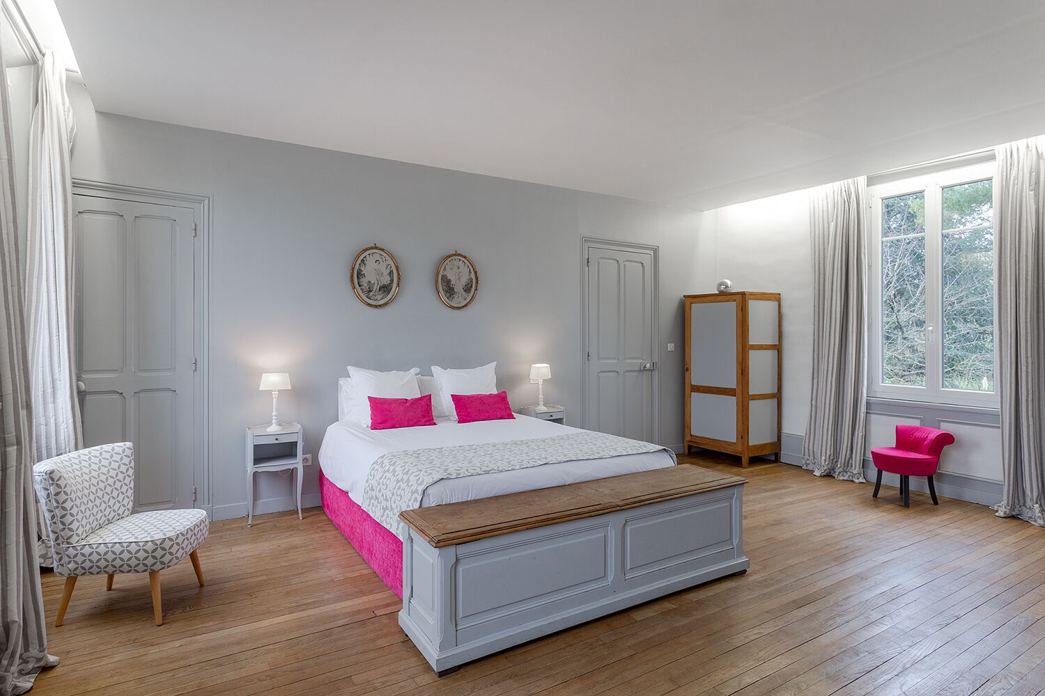 Un dormitorio con cama, mesitas de noche, una silla, armario y ventana.