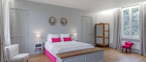 A bedroom with a bed, bedside tables, a chair, a wardrobe, and a window.