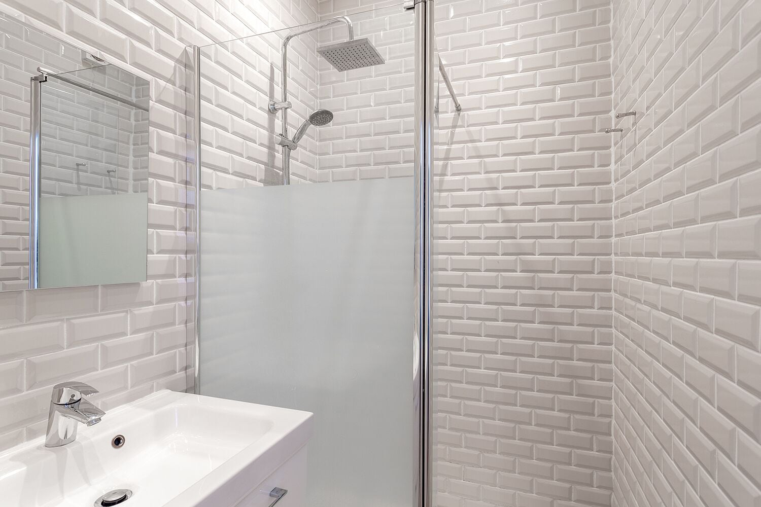 Une salle de bain avec un lavabo blanc, un miroir et une cabine de douche.