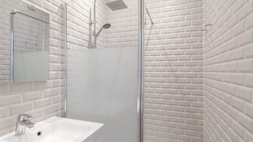 Une salle de bain avec un lavabo blanc, un miroir et une cabine de douche.