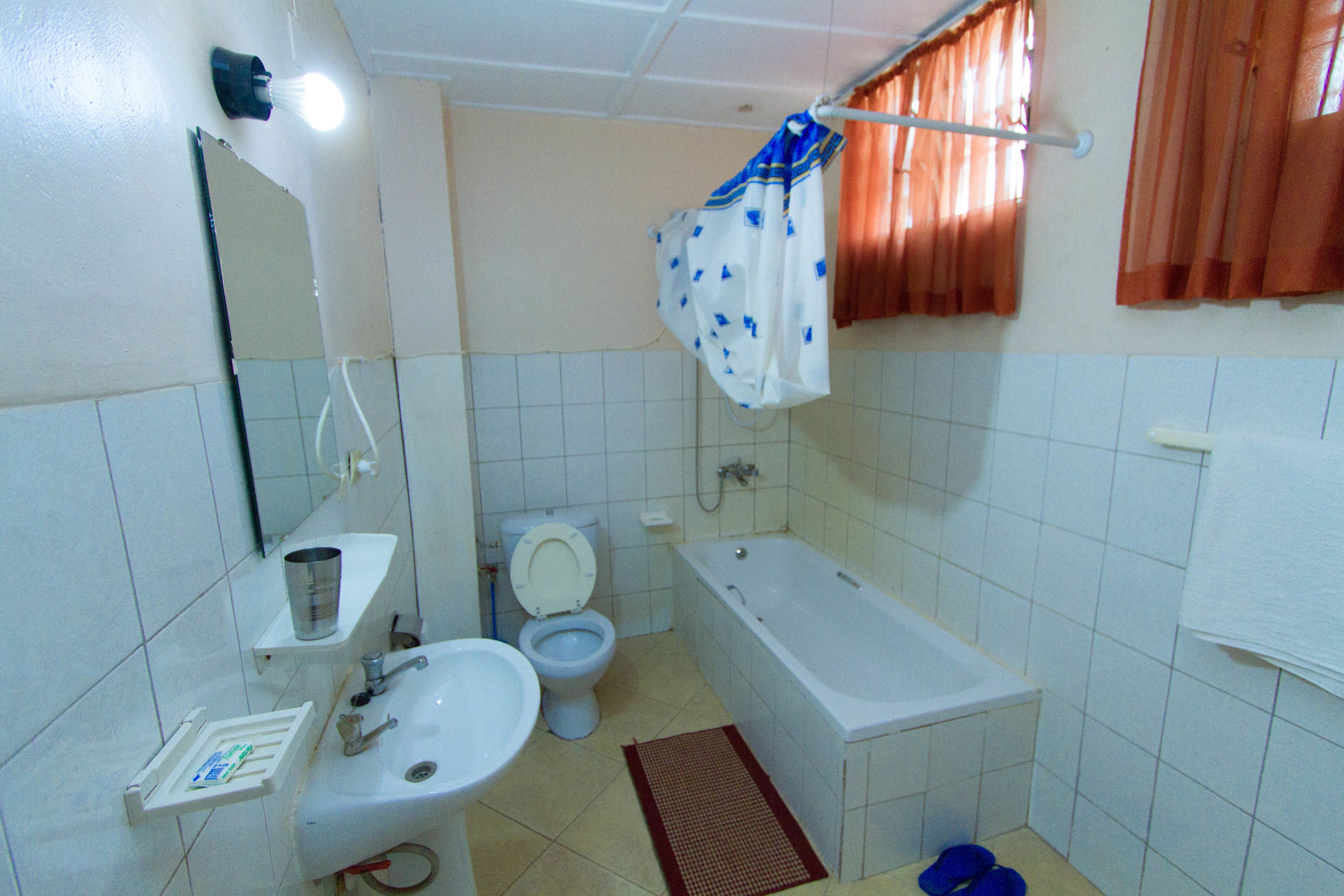 Et badeværelse med toilet, vask og badekar.