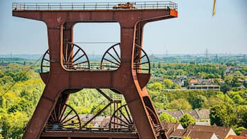 Una gran estructura metálica oxidada con una escalera y una plataforma, con vistas a una localidad con casas y vegetación.