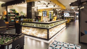 A modern lobby with a reception desk, seating area, and various amenities including a shop, lift, water, self-check-in, and photo booth. - Holiday Inn - the niu, Cobbles Essen by IHG (Essen)