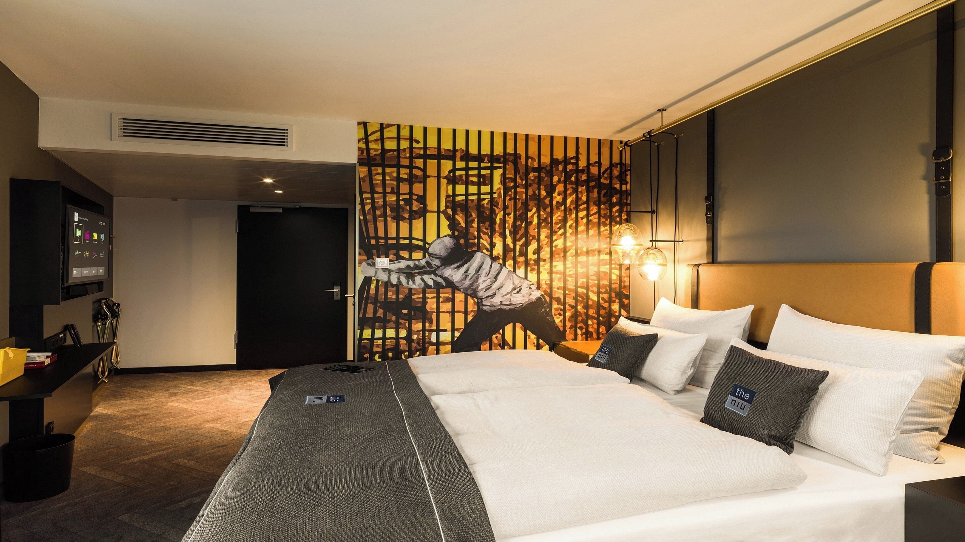 Habitación de hotel con una cama grande, televisor montado en la pared y un diseño de pared original.