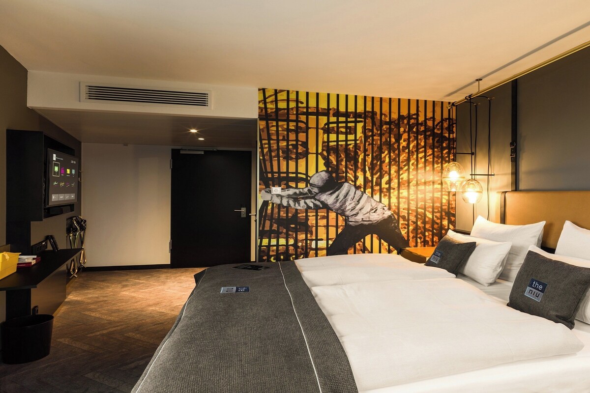 Ein Hotelzimmer mit einem großen Bett, einem an der Wand montierten Fernseher und einem einzigartigen Wanddesign.