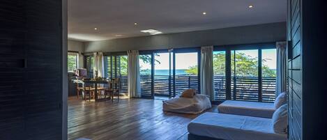 Ein modernes Hotelzimmer mit einem großen Bett, einer Sitzecke und Blick auf das Meer.