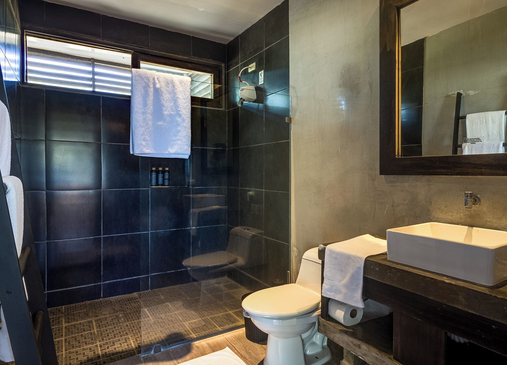 Un baño moderno con ducha acristalada, inodoro y lavabo.