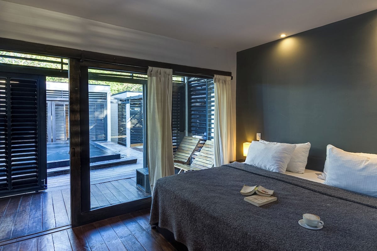 A bedroom with a bed, pillows, a cup, and a book on the bed.