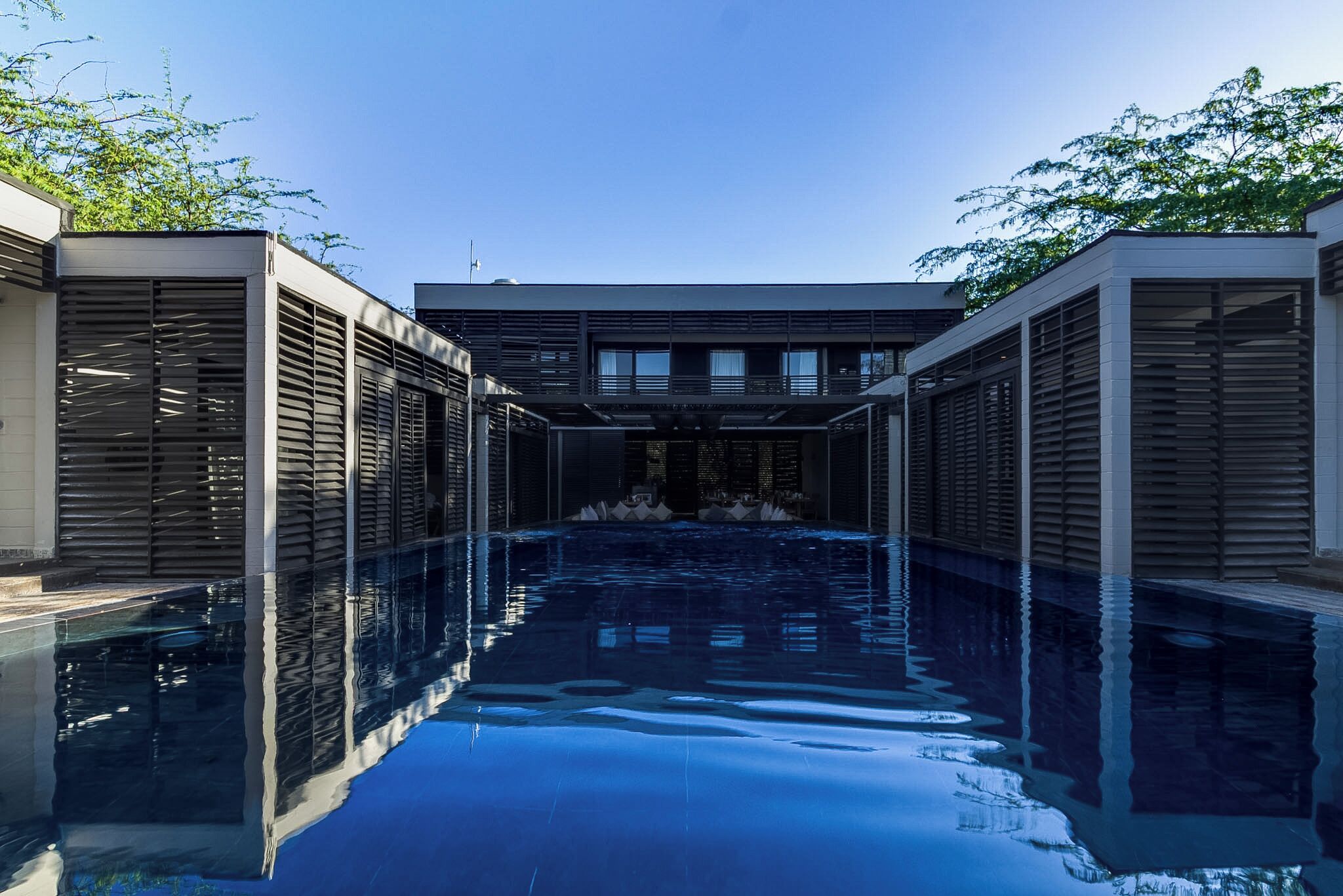 Un edificio moderno con una piscina al centro, circondato da alberi.