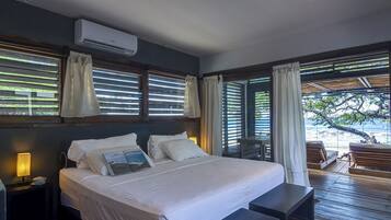 Un dormitorio con cama, mesitas de noche y vista al océano.