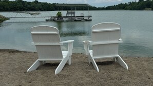 Two white Adirondack chairs facing a dock with a boat and a bench. - The B & B at Queenslake (Georgetown)