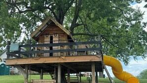 A wooden playhouse with a slide, a bench, and a small garden area. - The B & B at Queenslake (Georgetown)