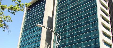 A modern building with a glass facade, a street lamp, and a car parked in front.