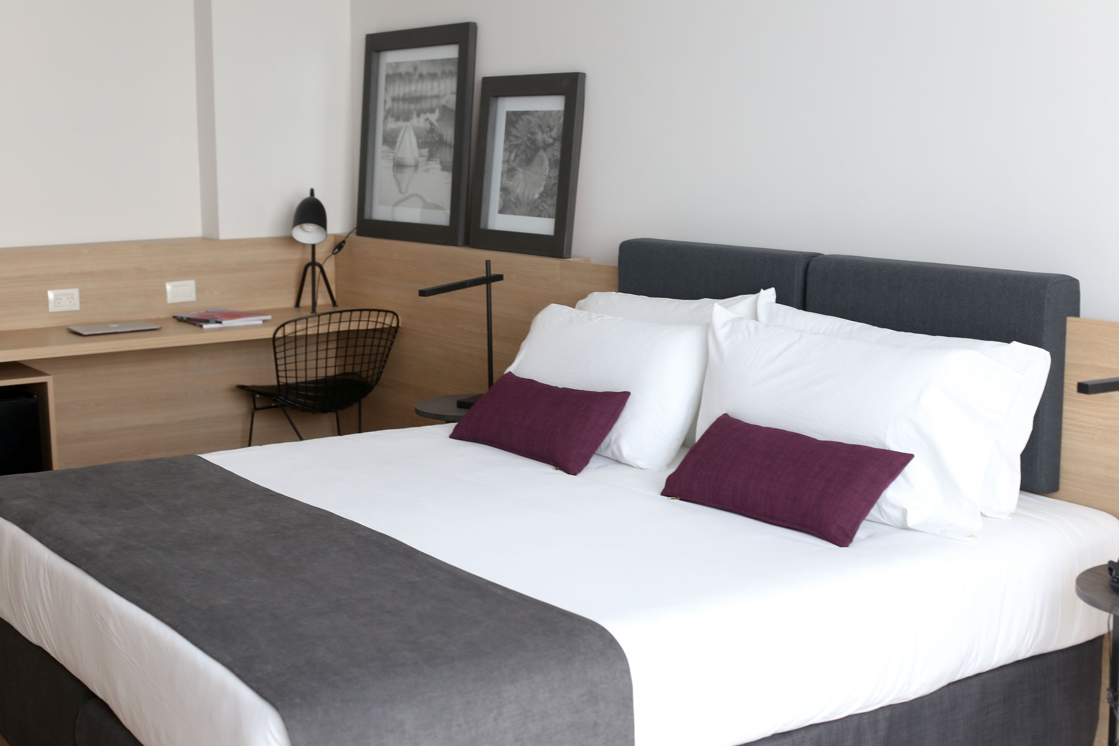A neatly arranged hotel room with a bed, a desk, and a chair.