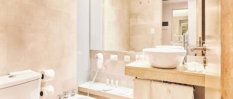 Un baño moderno con inodoro, bidé, lavamanos y un espejo grande.