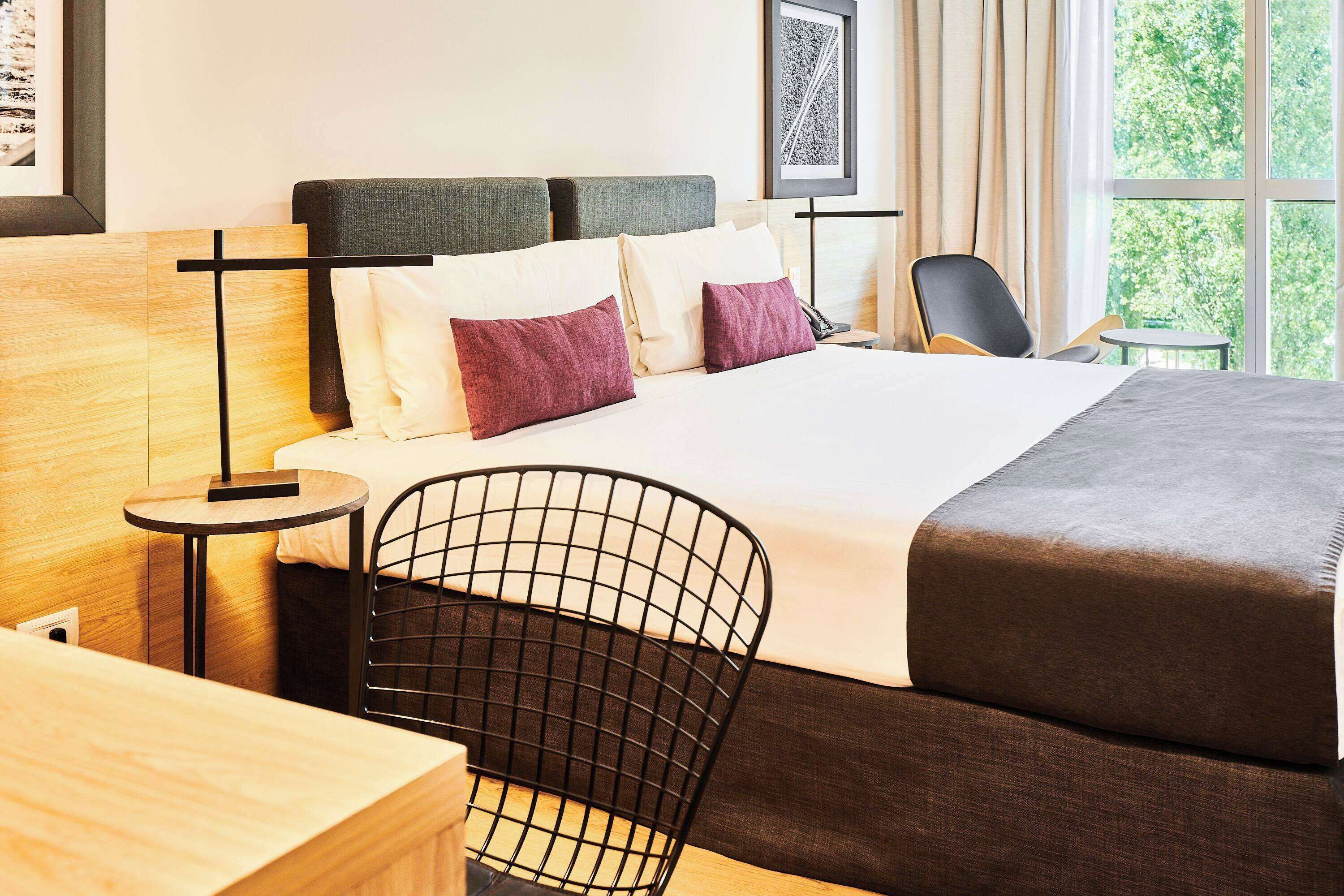 Una habitación de hotel moderna con una cama grande, un escritorio y una silla.