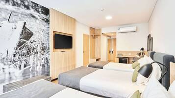 Una habitación de hotel con tres camas, televisión, escritorio y baño.
