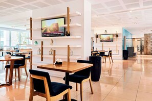 A modern restaurant with wooden tables and chairs, a TV mounted on a white wall, and a bright, spacious interior. - Dazzler by Wyndham Rosario (Rosario)