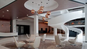 Un vestíbulo amplio con asientos modernos, una escalera central y un suelo con diseño.