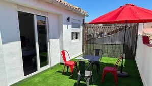 A patio with a table and chairs, a red umbrella, and a wooden fence. - Hostel Malaga City (Malaga)