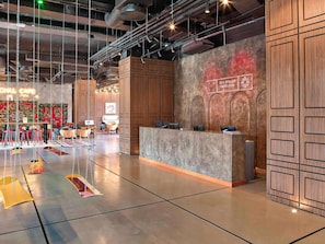 A modern interior with a reception desk, seating area, and a colorful mural. - ibis Styles Sarajevo (Sarajevo)