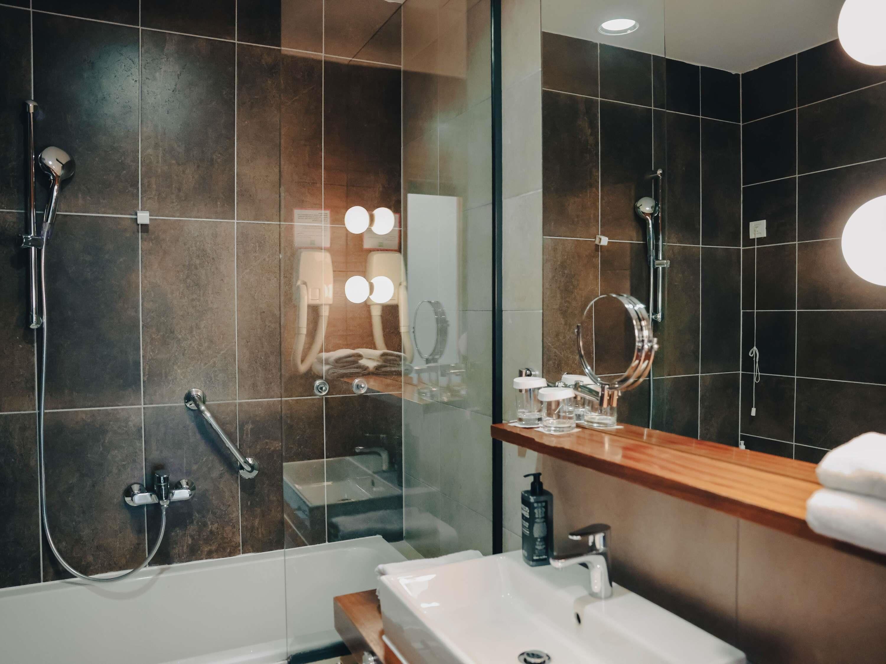 A modern bathroom with a glass shower enclosure, a vanity with a mirror, and a sink.