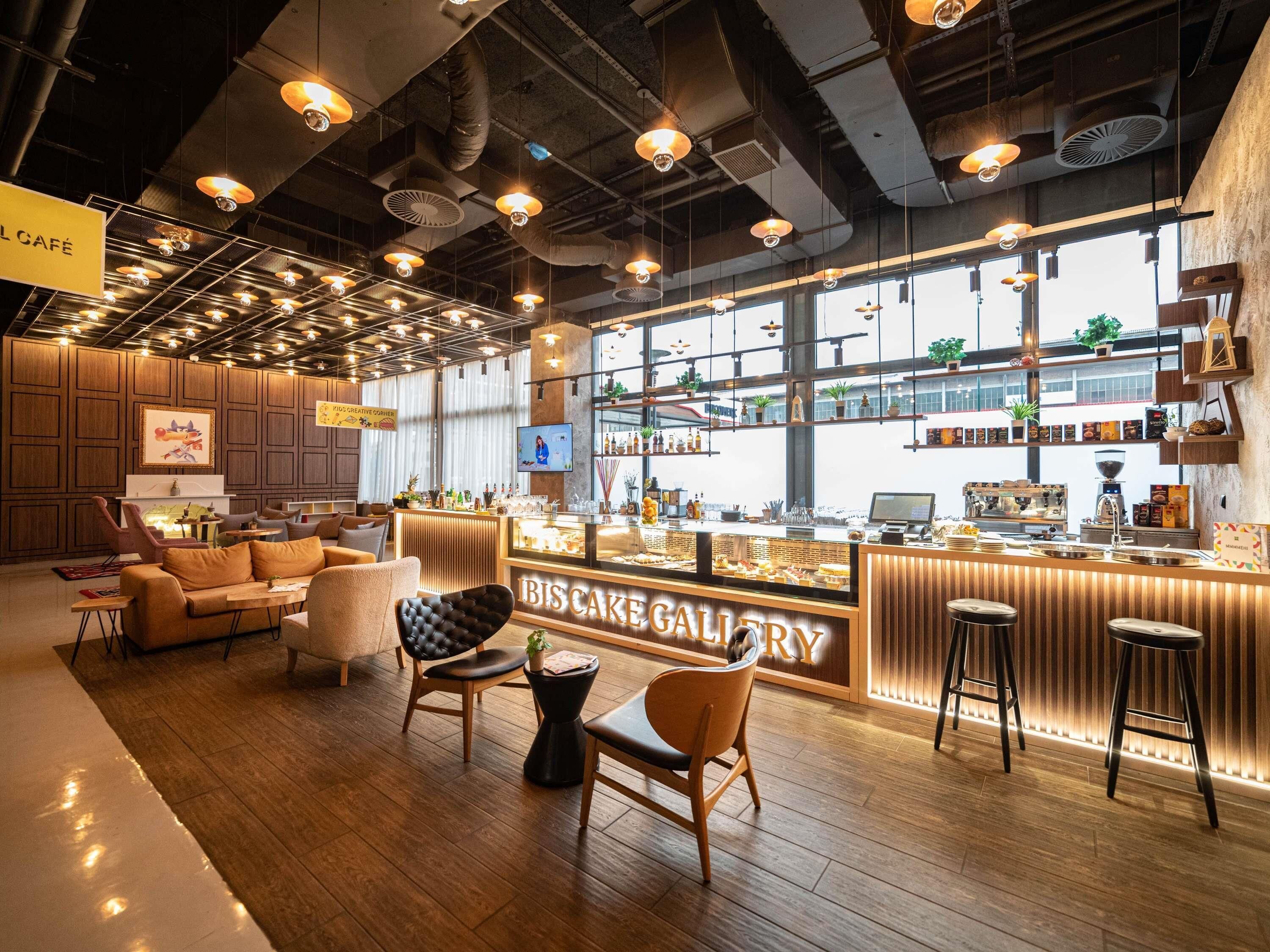 A modern café interior with wooden furniture, a bar area, and a large window providing natural light.