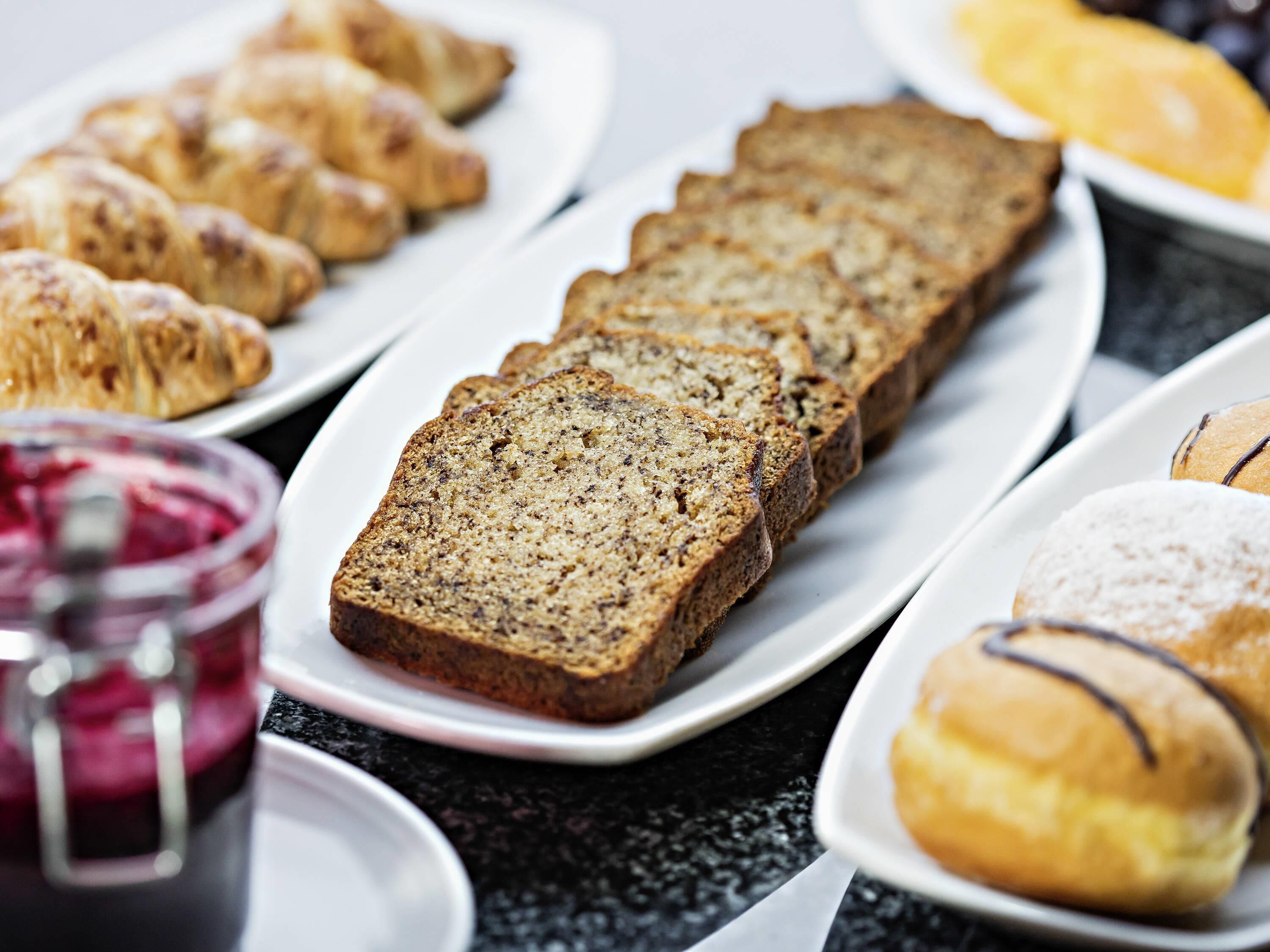 Variedad de pasteles en una mesa, incluyendo croissants y muffins.