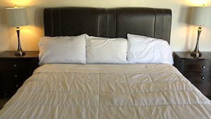 Una cama bien hecha con un cabecero acolchado y dos lámparas de noche.