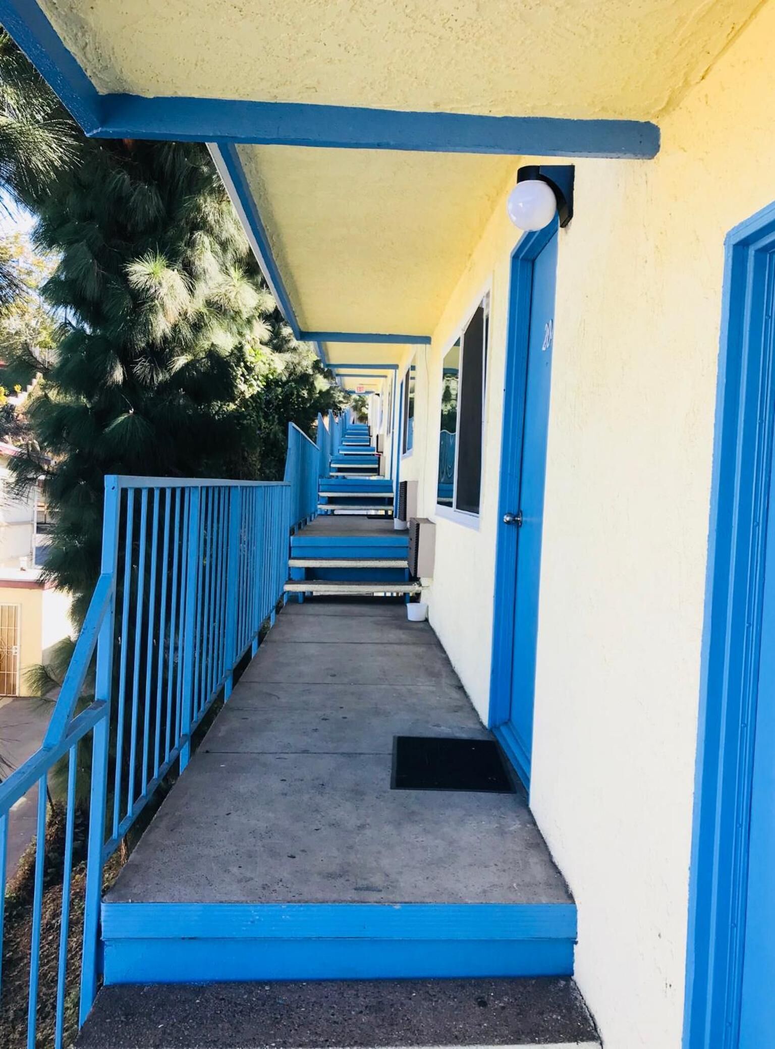 Un couloir avec des rampes bleues et des marches menant à une porte dotée d’une fenêtre.
