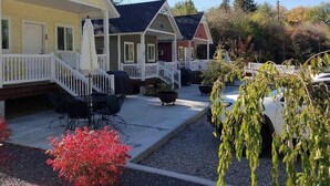 A row of houses with white railings, outdoor seating, and a gravel driveway.