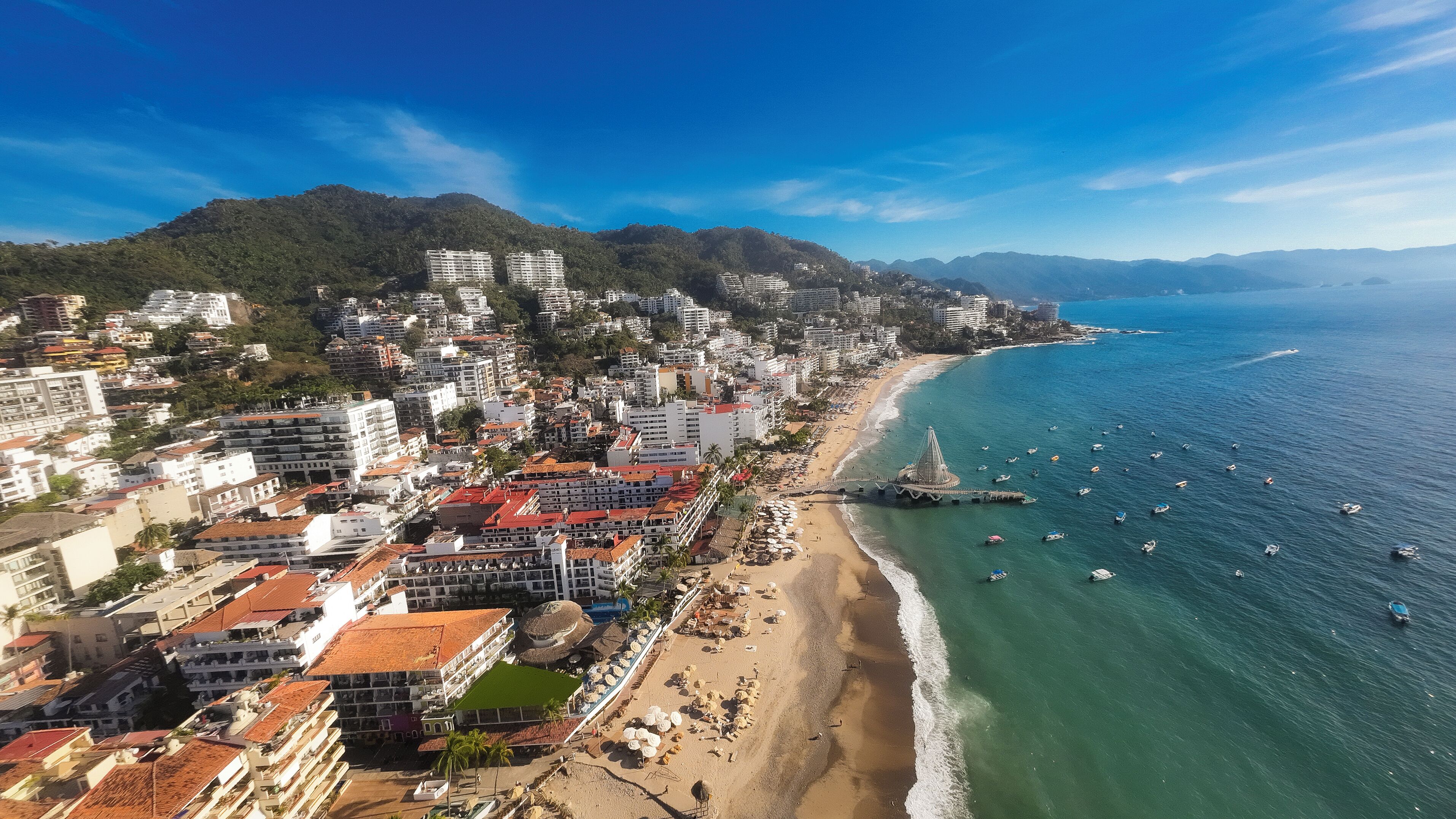 A coastal cityscape with a beach, buildings, and boats.